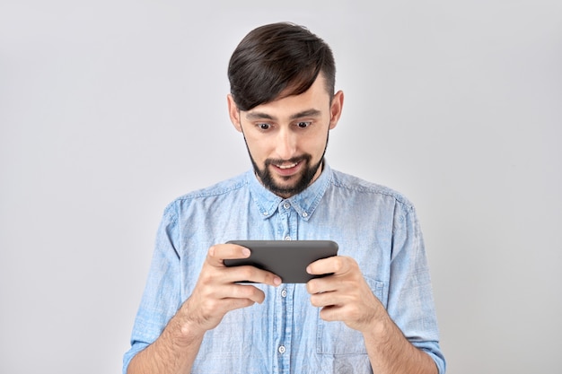 Junger Mann, der Spiele auf Smartphone isoliert spielt