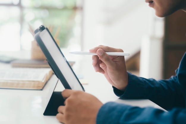 Junger mann, der stift und digitales tablett für online-lernen und kommunikation verwendet.