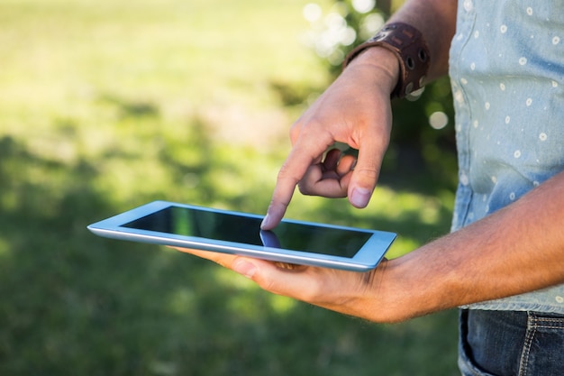 Junger Mann, der Tablette im Park verwendet