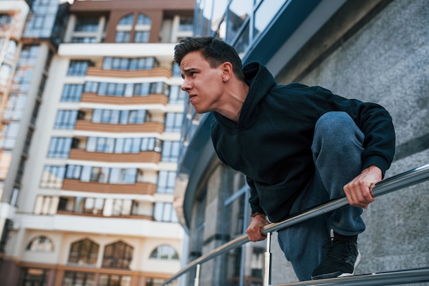 Junger Mann, der tagsüber Parkour in der Stadt macht. Konzeption von Extremsportarten.