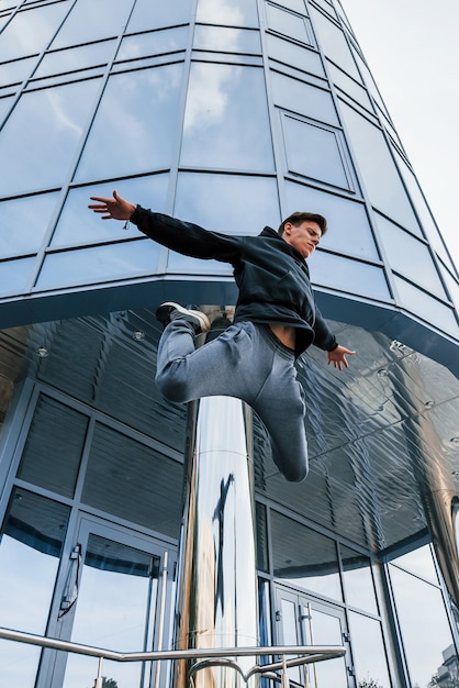 Junger Mann, der tagsüber Parkour in der Stadt macht. Konzeption von Extremsportarten.