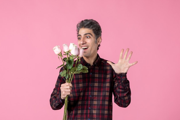 Junger Mann der Vorderansicht mit schönen rosa Rosen auf rosa Wand