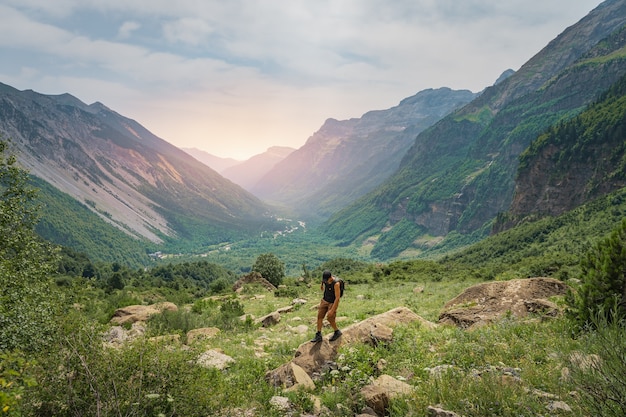 Junger Mann, der während des Sonnenuntergangs auf einem grünen Berg trekking