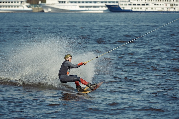 Junger Mann, der Wakeboard auf einem Sommersee reitet