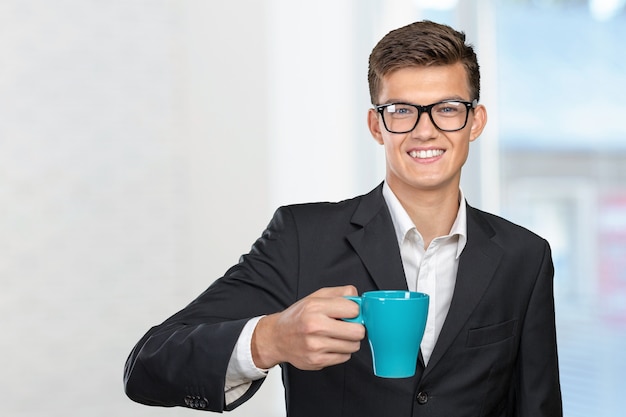 Junger Mann, der warme Tasse Tee / Kaffee hält
