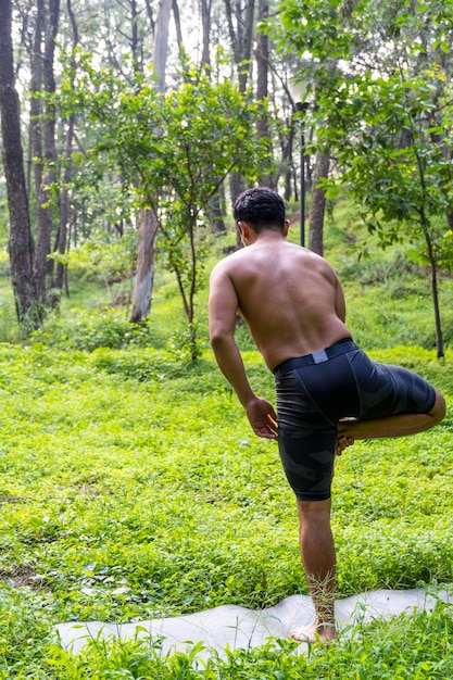 Junger mann, der yoga oder reiki im wald tut sehr grüne vegetation in mexiko guadalajara bosque colomos hispanic