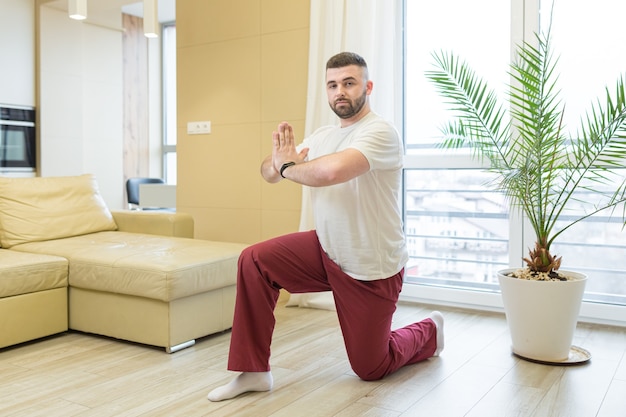Junger Mann, der Yoga zu Hause tut