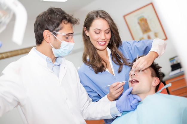 Junger Mann, der zahnmedizinischen Chekup im Zahnarztbüro hat