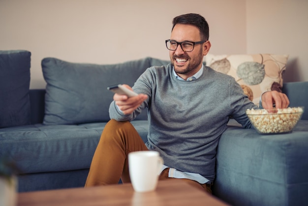 Junger Mann, der zu Hause auf einem Sofa fernsieht