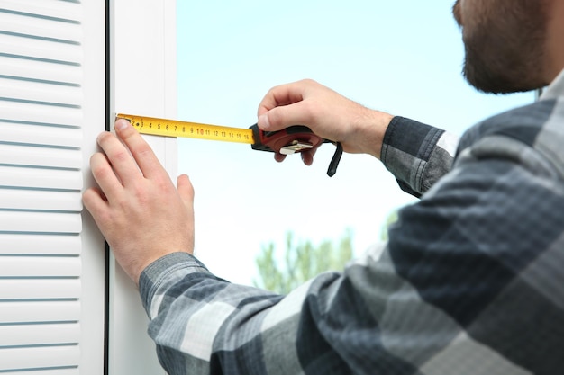 Junger Mann, der zu Hause Jalousien installiert