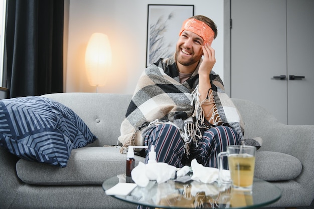 Foto junger mann, der zu hause unter kälte leidet aufnahme eines jungen mannes, der auf seinem bett sitzt und sich zu hause unwohl fühlt versucht, warm zu bleiben kranker mann