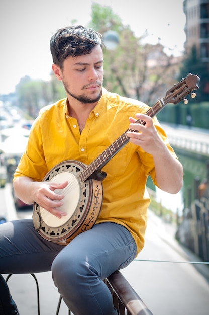 Junger Mann des Hippies, der Banjo spielt