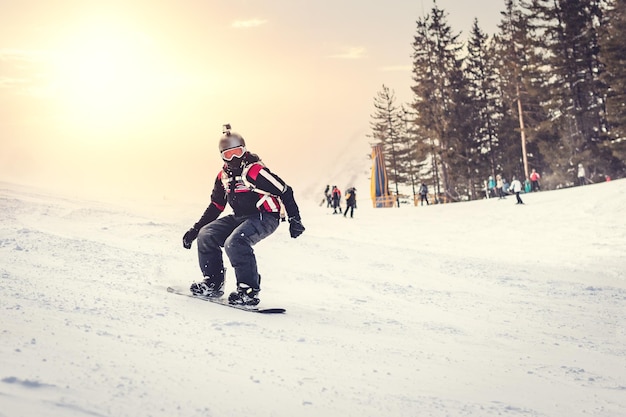 Junger Mann fährt Snowboard und genießt einen gefrorenen Wintertag an Berghängen.