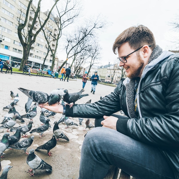 Junger Mann füttert Tauben im Stadtpark
