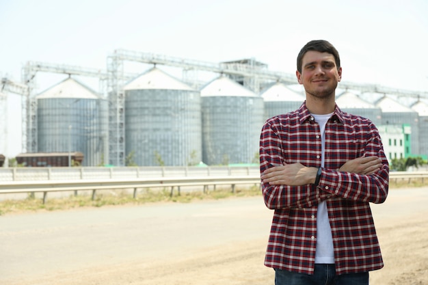 Junger Mann gegen Getreidesilos. Landwirtschaftsgeschäft