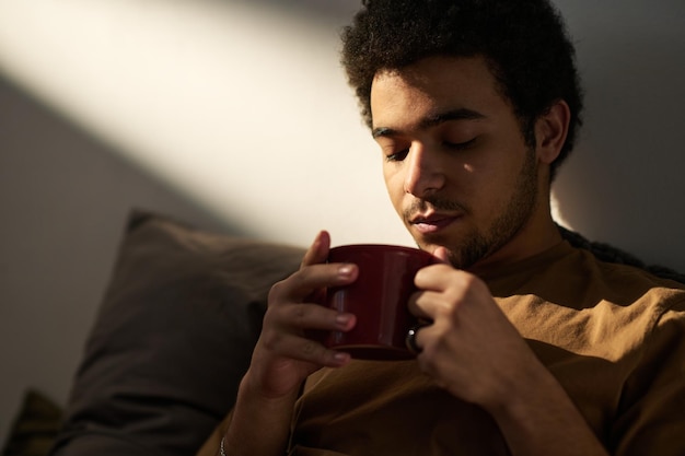 Junger Mann genießt heißen Kaffee