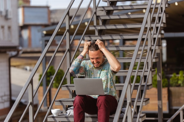 Junger Mann, Geschäftsmann auf der Suche nach Job mit Laptop im Freien,