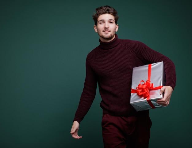 Junger Mann, Geschenkboxen rote Seide Bögen Neujahr Weihnachten Modefoto Studioaufnahme Grüner Hintergrund