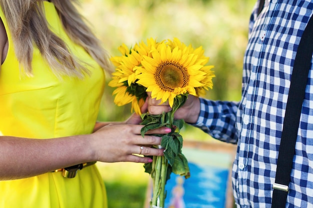 Junger Mann gibt einen Strauß Sonnenblumen