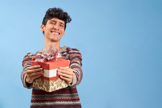 Junger Mann glücklich mit Weihnachtsgeschenk isoliert