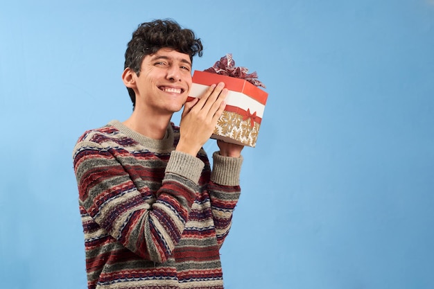 Junger Mann glücklich mit Weihnachtsgeschenk isoliert