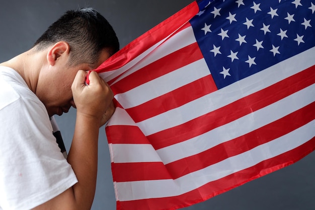 Foto junger mann hält die nationalflagge der vereinigten staaten von amerika und zeigt dankbarkeit