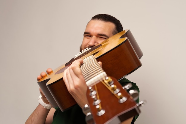 Foto junger mann hält eine akustikgitarre und schaut, ob der hals gerade ist