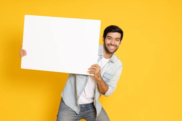 Foto junger mann hält weißes leeres banner auf gelbem hintergrund blick in die kamera