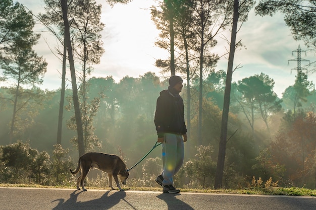 Junger Mann hat Spaß mit seinem Hund in der Natur mit den Strahlen der Morgensonne warm leuchten