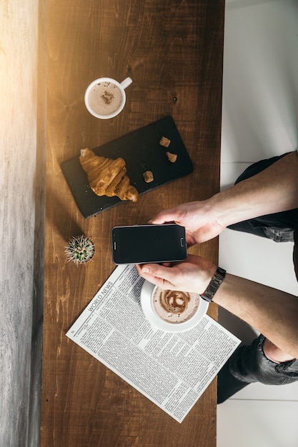 Junger Mann im Café las Zeitung mit starkem Kaffee