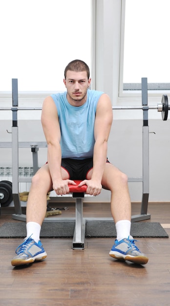 junger mann im fintess sportclub trainiert mit gewichten und entspannt sich