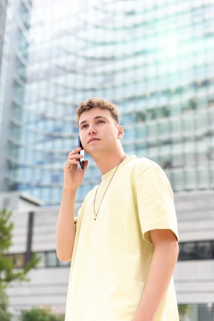 Junger Mann im gelben T-Shirt telefoniert auf der Straße