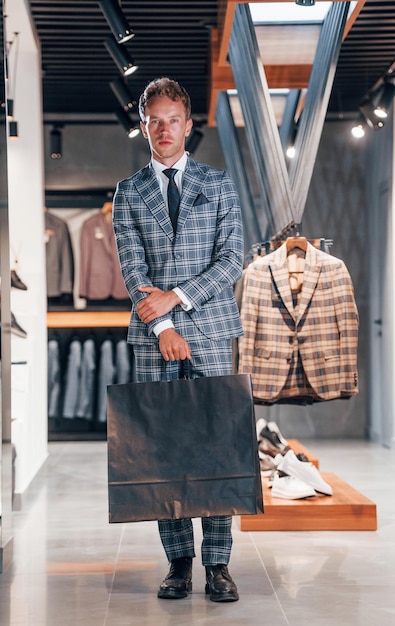Junger Mann im modernen Laden mit neuer Kleidung Elegante, teure Kleidung für Männer