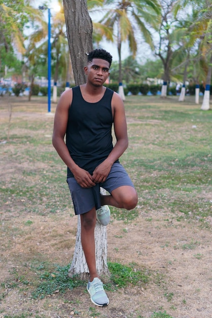 Foto junger mann im park an den baum gelehnt