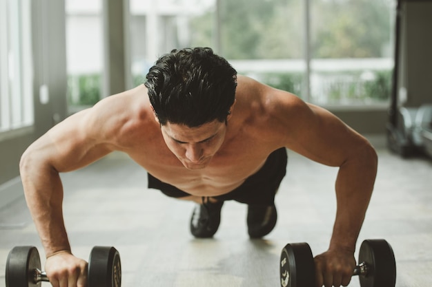 Junger Mann im Training drückt sich zu Hause im Fitnessstudio hoch