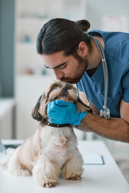 Junger Mann in blauer Uniform, der Yorkshire-Terrier küsst und kuschelt