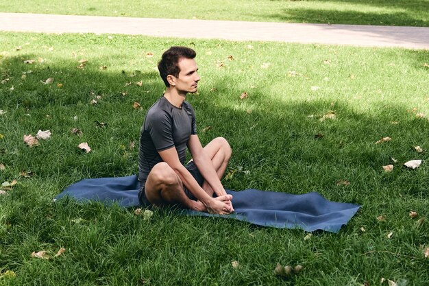 Junger Mann in der Sportbekleidung, die Yoga im Park tut