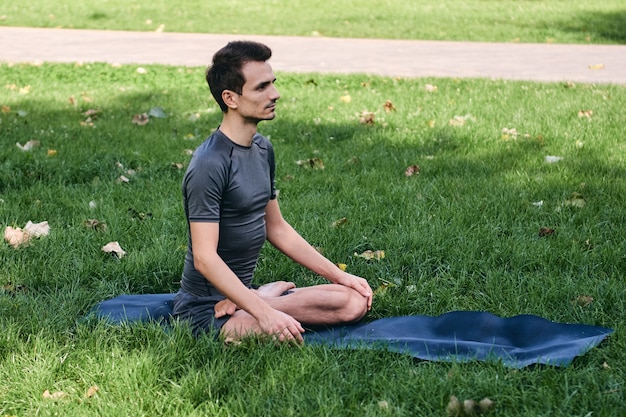 Junger Mann in der Sportbekleidung, die Yoga im Park tut