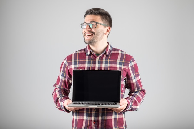 Junger Mann in einem Hemd, das einen Laptop hält