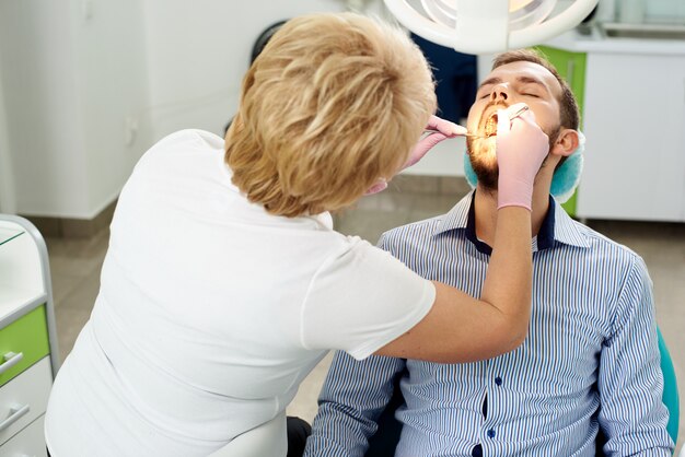 Junger Mann in einem Zahnarztstuhl auf einer Untersuchung bei einem Zahnarzt in einer modernen Klinik.