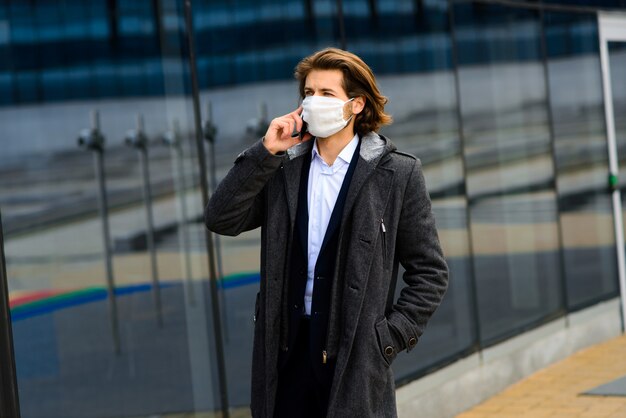 Junger Mann in einer medizinischen Maske draußen, kein Geld, Krise, Armut, Not. Quarantäne, Coronavirus, Isolierung.