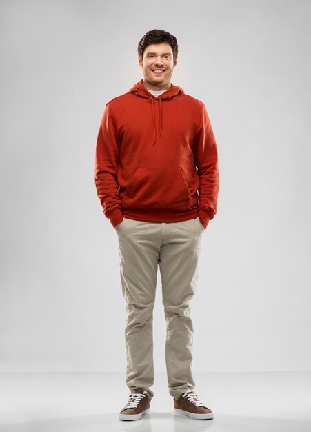 junger Mann in rotem Hoodie auf grauem Hintergrund