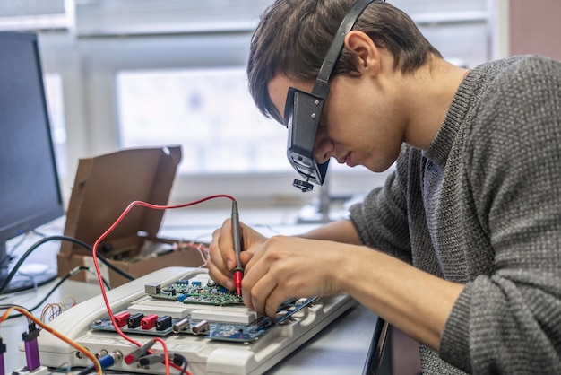 Junger Mann in speziellen Zoombrillen arbeitet mit Silizium-Elektronikchip b