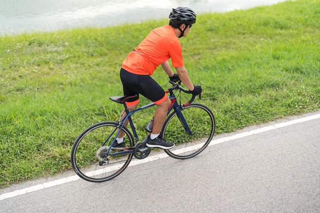 Junger Mann in Sportkleidung Radfahrer radelt an einem sonnigen Tag draußen auf einem Rennrad Sportliche Aktivität auf schwarzem Fahrrad