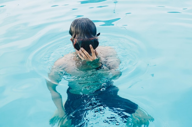 Junger Mann in Tauchermaske schwimmt in einem Pool vorne kriechen