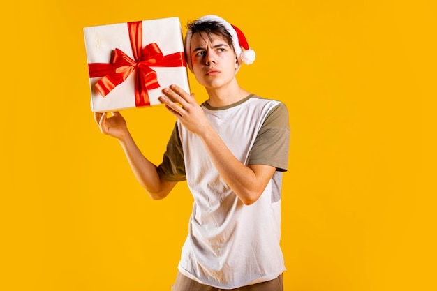 Junger Mann ist überrascht mit einer Geschenkbox in seinen Händen auf gelbem Hintergrund