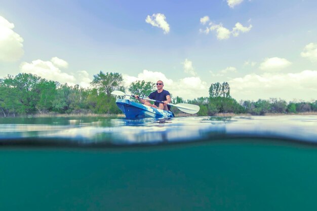 Junger Mann Kajakfahren auf dem See, Kajakfahren unter Wasser, Split Shot.