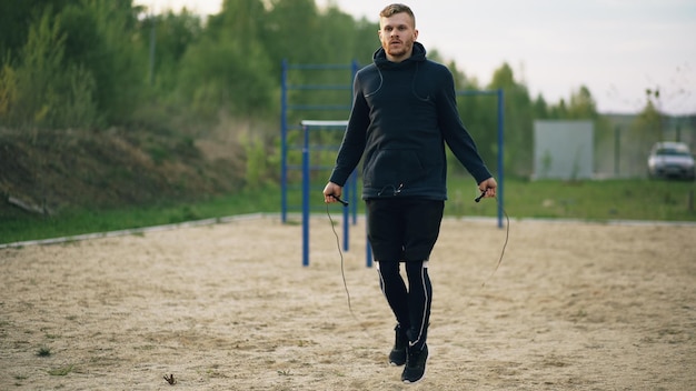 Junger Mann Kickboxer Training mit Springseil im Stadtpark