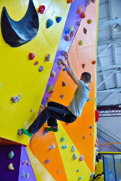 Junger Mann klettert im Fitnessstudio auf die Übungswand