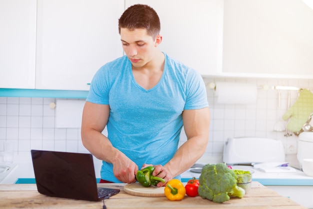 Junger Mann kocht gesunde Mahlzeit Gemüse Computer Internet Essen